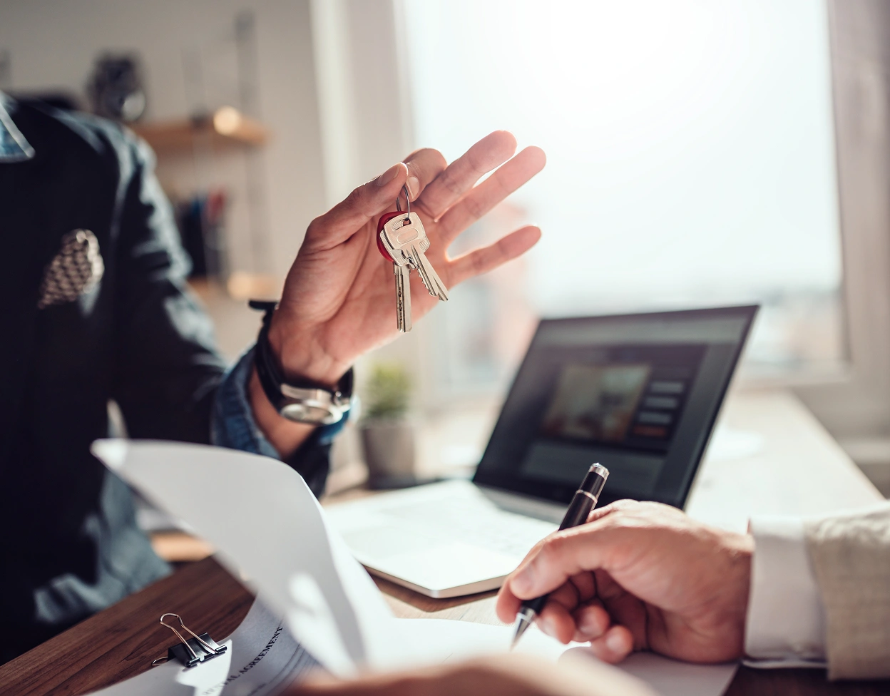 A landlord hands over keys during the signing of a lease